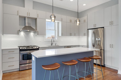 Large transitional l-shaped medium tone wood floor, brown floor and tray ceiling eat-in kitchen photo in Chicago with an undermount sink, flat-panel cabinets, gray cabinets, quartz countertops, white backsplash, porcelain backsplash, stainless steel appliances, an island and white countertops