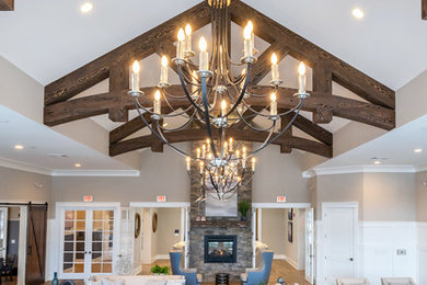 Example of a huge mountain style open concept carpeted and gray floor living room design in Philadelphia with gray walls, a two-sided fireplace, a stone fireplace and a wall-mounted tv