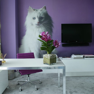 Bild på ett funkis arbetsrum, med lila väggar, ett fristående skrivbord och grått golv