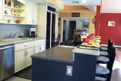 Mid-sized elegant single-wall ceramic tile and beige floor eat-in kitchen photo in Newark with gray backsplash, black appliances, an island, a drop-in sink, raised-panel cabinets, white cabinets, laminate countertops and stone slab backsplash