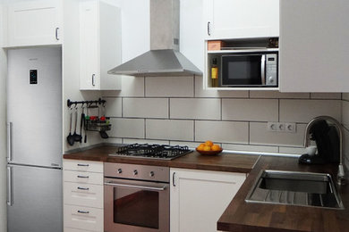 Foto de cocinas en L rústica de tamaño medio cerrada sin isla con fregadero de un seno, armarios con rebordes decorativos, puertas de armario blancas, encimera de madera, salpicadero metalizado, salpicadero de metal, electrodomésticos de acero inoxidable, suelo de baldosas de cerámica y suelo marrón