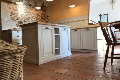 This is an example of a medium sized farmhouse l-shaped kitchen/diner in Angers with a built-in sink, shaker cabinets, white cabinets, wood worktops, terracotta flooring, an island and pink floors.