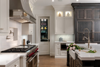 Huge transitional medium tone wood floor and brown floor kitchen photo in St Louis with recessed-panel cabinets, white cabinets, quartz countertops, quartz backsplash, paneled appliances, an island, white countertops, a farmhouse sink and white backsplash