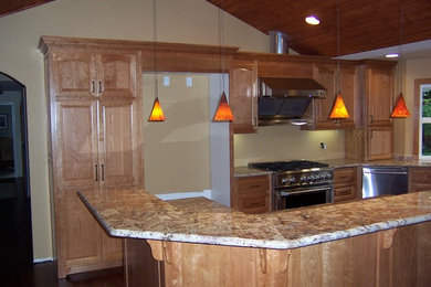 This is an example of a mid-sized traditional u-shaped separate kitchen in Sacramento with raised-panel cabinets, medium wood cabinets, granite benchtops, stainless steel appliances, dark hardwood floors, a peninsula and brown floor.