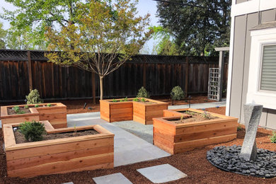 Foto de jardín de secano tradicional renovado de tamaño medio en patio trasero con macetero elevado, adoquines de piedra natural y con madera