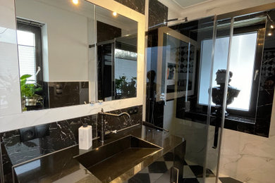 Klassisches Badezimmer mit schwarzen Schränken, bodengleicher Dusche, Wandtoilette mit Spülkasten, schwarz-weißen Fliesen, Keramikfliesen, weißer Wandfarbe, Keramikboden, integriertem Waschbecken, Marmor-Waschbecken/Waschtisch, Schiebetür-Duschabtrennung, schwarzer Waschtischplatte und Einzelwaschbecken in Sonstige