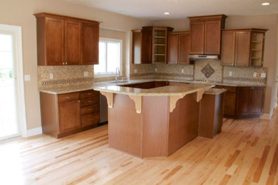 Mid-sized elegant l-shaped light wood floor eat-in kitchen photo in Cleveland with a double-bowl sink, recessed-panel cabinets, medium tone wood cabinets, granite countertops, multicolored backsplash, mosaic tile backsplash, stainless steel appliances and an island