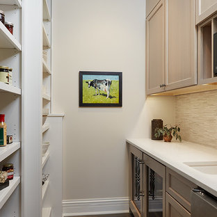 Cette photo montre une petite arrière-cuisine parallèle chic avec un évier encastré, un placard à porte shaker, des portes de placard en bois brun, un plan de travail en quartz modifié, une crédence beige, une crédence en carreau briquette, un électroménager en acier inoxydable, un sol en bois foncé, aucun îlot et un sol marron.