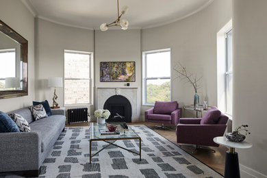 Example of a large trendy open concept medium tone wood floor living room design in New York with gray walls, a standard fireplace, a stone fireplace and a wall-mounted tv