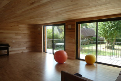 Cette image montre un grand studio de yoga minimaliste avec un mur marron, parquet clair et un sol marron.