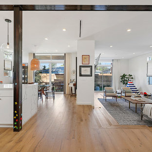 Inspiration för moderna allrum med öppen planlösning, med vita väggar, ljust trägolv, en hängande öppen spis, en spiselkrans i gips, en inbyggd mediavägg och brunt golv