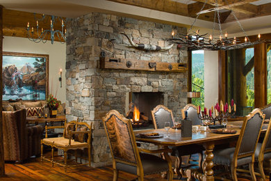 Inspiration for a rustic dining room in Other with beige walls, dark hardwood flooring, a two-sided fireplace, a stacked stone fireplace surround, brown floors and exposed beams.