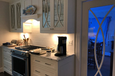 This is an example of a medium sized traditional l-shaped enclosed kitchen in DC Metro with a submerged sink, shaker cabinets, white cabinets, marble worktops, white splashback, metro tiled splashback, integrated appliances, an island, brown floors and dark hardwood flooring.