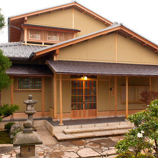 Bild på ett orientaliskt beige hus, med två våningar och sadeltak