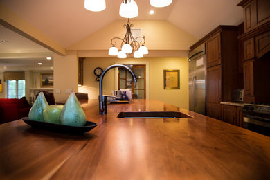 Inspiration for a mid-sized timeless open concept kitchen remodel in Boston with a single-bowl sink, raised-panel cabinets, dark wood cabinets, granite countertops, stainless steel appliances and an island