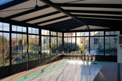 Ejemplo de casa de la piscina y piscina clásica renovada grande rectangular en patio lateral con suelo de baldosas