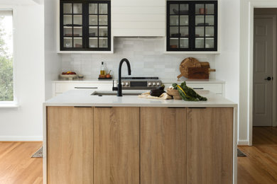 Inspiration for a small modern l-shaped light wood floor and brown floor eat-in kitchen remodel in DC Metro with an undermount sink, shaker cabinets, black cabinets, quartz countertops, gray backsplash, ceramic backsplash, stainless steel appliances, an island and white countertops