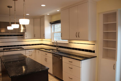 Design ideas for a mid-sized transitional u-shaped eat-in kitchen in DC Metro with an undermount sink, flat-panel cabinets, white cabinets, white splashback, ceramic splashback, stainless steel appliances, porcelain floors, with island, quartz benchtops, beige floor and black benchtop.
