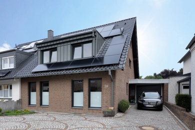 Mittelgroßes, Zweistöckiges Modernes Einfamilienhaus mit Backsteinfassade, roter Fassadenfarbe, Satteldach, Ziegeldach, schwarzem Dach und Dachgaube in Düsseldorf