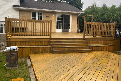Large backyard ground level wood railing deck photo in Montreal