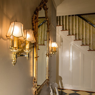 Klassisk inredning av en liten hall, med beige väggar, målat trägolv och flerfärgat golv