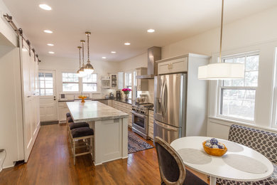Inspiration for a mid-sized country l-shaped medium tone wood floor and brown floor enclosed kitchen remodel in Other with white cabinets, marble countertops, white backsplash, subway tile backsplash, stainless steel appliances, an island, a farmhouse sink and recessed-panel cabinets