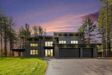 Mid-sized minimalist brick and clapboard house exterior photo in Grand Rapids with a shed roof, a metal roof and a black roof
