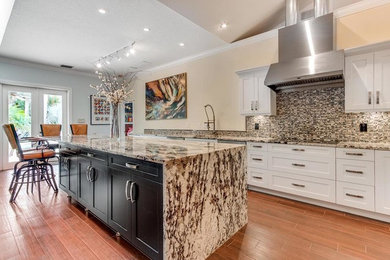 Inspiration for a large contemporary l-shaped dark wood floor and red floor eat-in kitchen remodel in Miami with an undermount sink, shaker cabinets, white cabinets, granite countertops, multicolored backsplash, stone tile backsplash, stainless steel appliances, an island and brown countertops