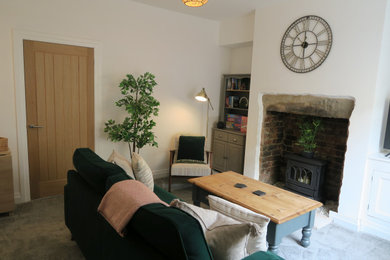 Ejemplo de salón cerrado tradicional renovado pequeño con paredes blancas, moqueta, marco de chimenea de piedra, televisor independiente y suelo gris