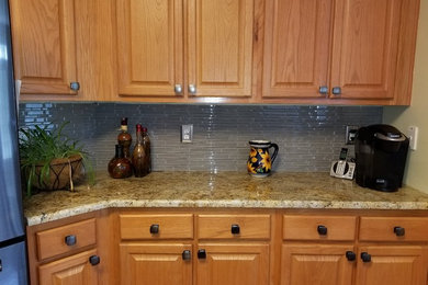 Mid-sized transitional kitchen photo in Other with raised-panel cabinets, light wood cabinets, granite countertops, gray backsplash, glass tile backsplash and stainless steel appliances
