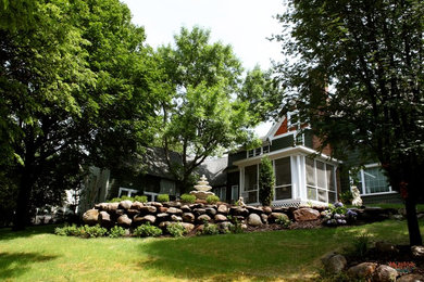 This is an example of a large rustic partial sun backyard concrete paver landscaping in Minneapolis for summer.