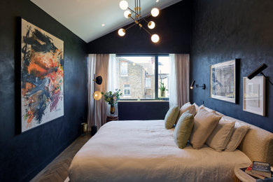 This is an example of a large contemporary master bedroom in London with black walls, medium hardwood flooring, brown floors, a vaulted ceiling and a feature wall.