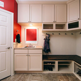 This is an example of a medium sized traditional u-shaped utility room in Other with a single-bowl sink, recessed-panel cabinets, white cabinets, red walls, porcelain flooring, a side by side washer and dryer, brown floors and beige worktops.