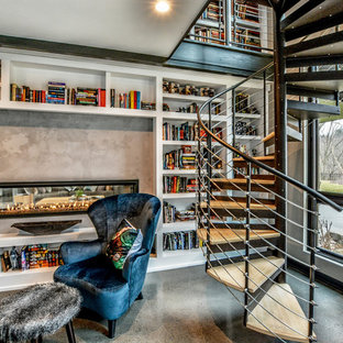 Foto på ett stort funkis arbetsrum, med ett bibliotek, beige väggar, betonggolv, en dubbelsidig öppen spis, en spiselkrans i betong, beiget golv och ett fristående skrivbord