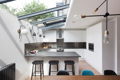 Design ideas for a medium sized contemporary u-shaped kitchen in London with flat-panel cabinets, white cabinets, metallic splashback and a breakfast bar.