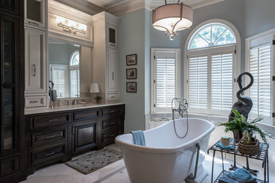 Ejemplo de cuarto de baño principal clásico de tamaño medio con armarios con paneles empotrados, puertas de armario de madera en tonos medios, bañera exenta, baldosas y/o azulejos beige y paredes azules