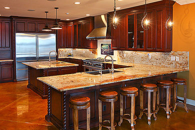 Large elegant u-shaped eat-in kitchen photo in Miami with a drop-in sink, raised-panel cabinets, dark wood cabinets, granite countertops, multicolored backsplash, stone slab backsplash, stainless steel appliances and an island