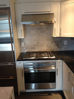 Side by side wall oven are mounted beneath white shaker cabinets