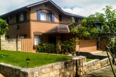 Large traditional two-storey brown house exterior in Hawaii with wood siding, a gable roof and a shingle roof.