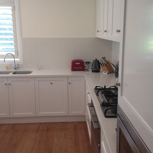 Mid-sized modern kitchen pantry remodeling - Kitchen pantry - mid-sized modern u-shaped medium tone wood floor kitchen pantry idea in Newcastle - Maitland with an undermount sink, recessed-panel cabinets, white cabinets, quartz countertops, stone slab backsplash and stainless steel appliances