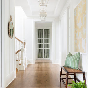 Exempel på en klassisk hall, med vita väggar, mellanmörkt trägolv och brunt golv