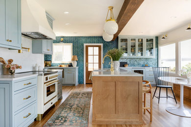 Example of a transitional l-shaped light wood floor, beige floor and exposed beam eat-in kitchen design in Seattle with recessed-panel cabinets, blue cabinets, white appliances, an island, white countertops, blue backsplash, mosaic tile backsplash and a farmhouse sink