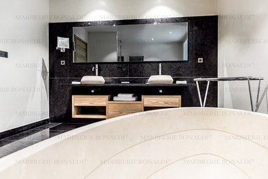 Idée de décoration pour une salle de bain principale design avec une baignoire posée, une douche à l'italienne, un carrelage noir, du carrelage en marbre, un mur gris, un sol en marbre, un lavabo posé, un plan de toilette en granite et un sol noir.