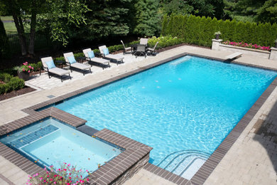 Example of a mid-sized transitional backyard brick and rectangular natural hot tub design in Detroit