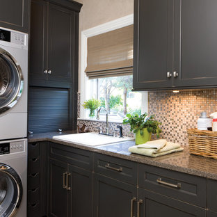 ミネアポリスのトラディショナルスタイルのおしゃれなランドリールーム (黒いキャビネット、上下配置の洗濯機・乾燥機、御影石カウンター、ベージュの壁、シェーカースタイル扉のキャビネット) の写真