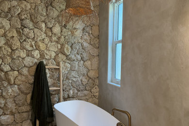 Example of a mid-sized island style master beige tile double-sink bathroom design in Tampa with flat-panel cabinets, light wood cabinets, beige walls, an undermount sink, quartzite countertops, a hinged shower door, beige countertops and a floating vanity