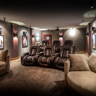 Example of a classic enclosed carpeted and brown floor home theater design in Omaha with gray walls and a projector screen