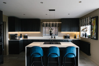 Contemporary grey and teal open plan kitchen in Other with shaker cabinets, grey cabinets, quartz worktops, integrated appliances, porcelain flooring, an island, white worktops and feature lighting.
