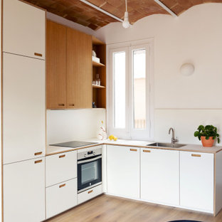 Diseño de cocina en L, actual, de tamaño medio, cerrada, con fregadero integrado, armarios estilo shaker, puertas de armario blancas, encimera de laminado, salpicadero blanco, salpicadero de azulejos de cerámica, electrodomésticos de acero inoxidable, suelo de contrachapado, suelo marrón y encimeras blancas