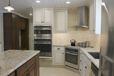 Inspiration for a country l-shaped porcelain tile open concept kitchen remodel in Philadelphia with an undermount sink, raised-panel cabinets, granite countertops, beige backsplash, stone tile backsplash, stainless steel appliances and an island